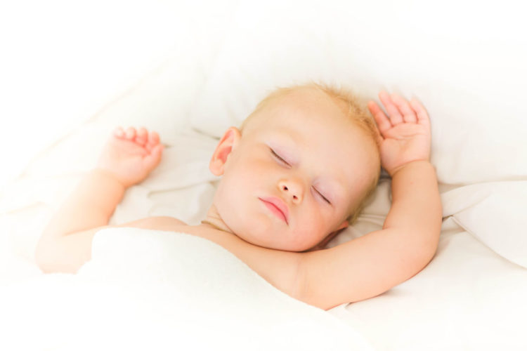 49609827 - peaceful baby lying on a bed sleeping on white sheets