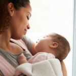 Close,Up,Of,Mother,Cuddling,Baby,Daughter,At,Home