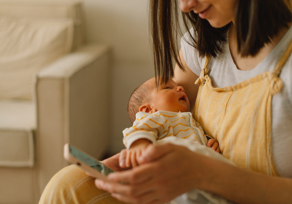 Mother,Sitting,On,Bed,And,Typing,On,The,Cellphone,While